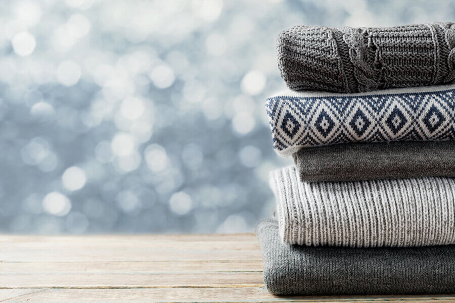 sweaters folded and stacked on top of wooden table